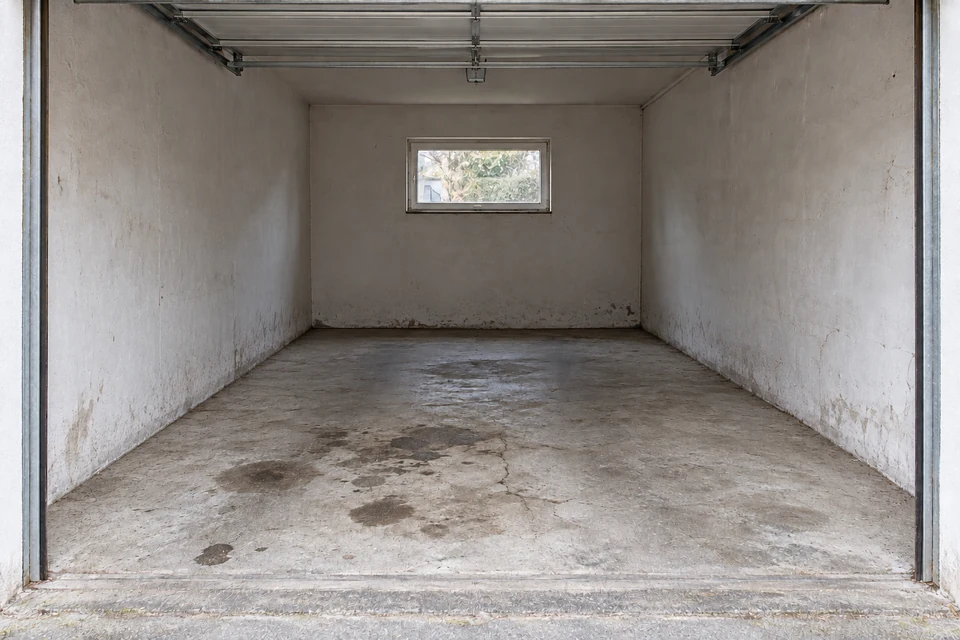Beispiel nach der Entrümpelung: dieselbe Garage leer und besenrein, mit erhaltenen Betonflecken und Gebrauchsspuren.